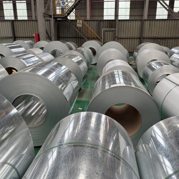 Slitting machine separating wide hot dipped galvanized steel coils into thin industrial strips.