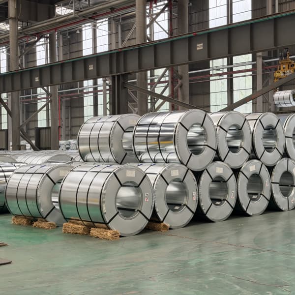 Heavy industrial trucks being loaded with galvanized steel coils inside our storage yard.